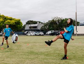 A film still from ‘Extreme Cake Sports’ with two contestants wearing blue jerseys playing rugby.