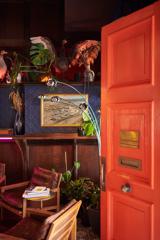 A dark room with eclectic decor and an orange door open on the right.