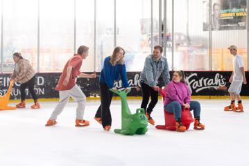 A group of people ice skating at Daytona Adventure Park in Upper Hutt, supporting themselves with two dolphin skate assists. People are skating in the background.