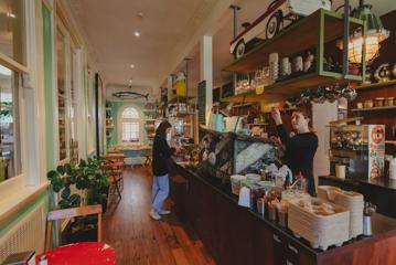 A customer at the counter while the barista makes coffees at The House of Good Fortune.