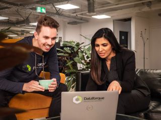 2 people looking at a laptop screen that has the data Tourque logo on it.