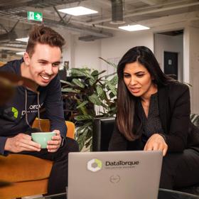 2 people looking at a laptop screen that has the data Tourque logo on it.