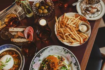 Various plates of food on a table at The Ram, including fries, oysters, olives, salami, and more.