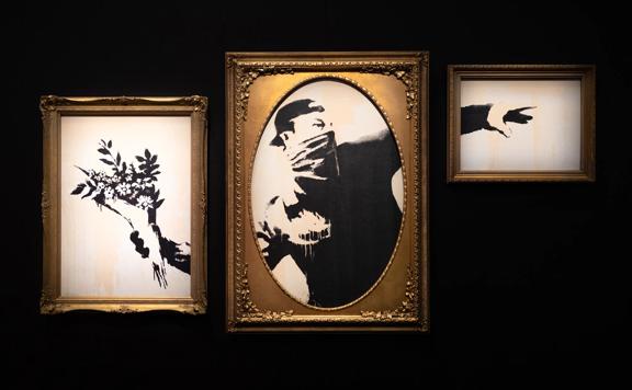 'The Flower Thrower' (2003) stencil mural by Banksy replicated as a framed triptych on display at The Art of Banksy exhibition.