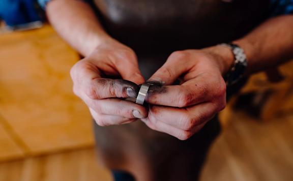 2 hands rubbing  black soot off of a silver ring made by Rawson Brothers Jewellery in Upper Hutt.