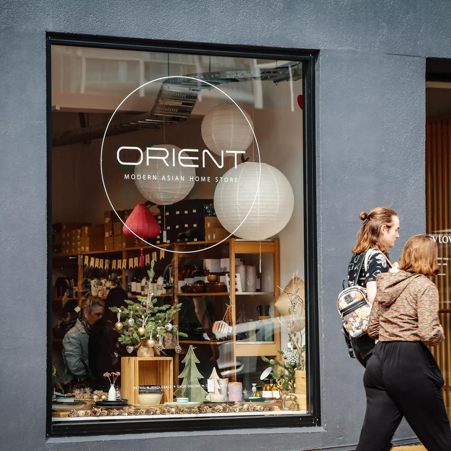 Two people walk by Orient's storefront. Orient Homewares and Gifts is a small gift shop located in Te Aro Wellington.