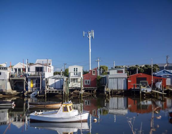 The Petone boat ramp, Hikoikoi,  with colourful boat sheds and boats in the morning sun.