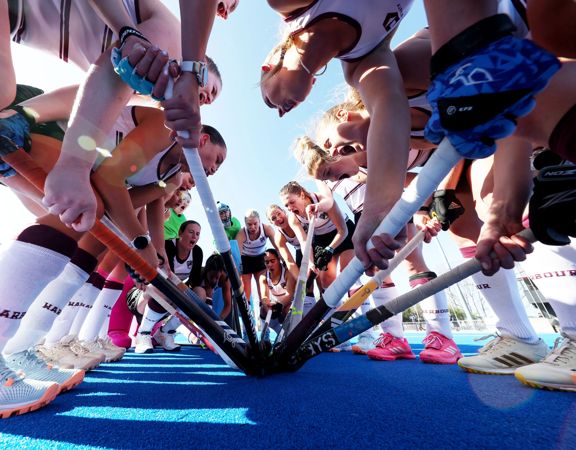 Field hockey players in a huddle.