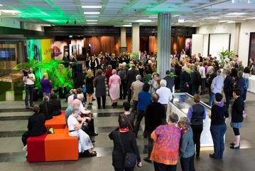 A large group of people standing inside the foyer of Tiakiwai Conference Centre - National Library of New Zealand.