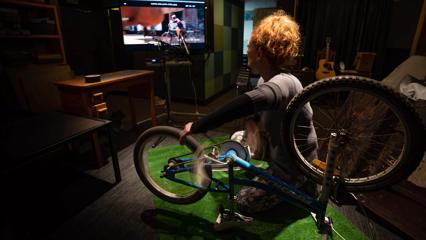 A person spins a bike wheel while watching a TV to make filey sound effects.