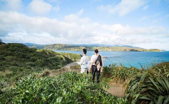 2 people looking out at pencarrow from the Eastern Walkway.