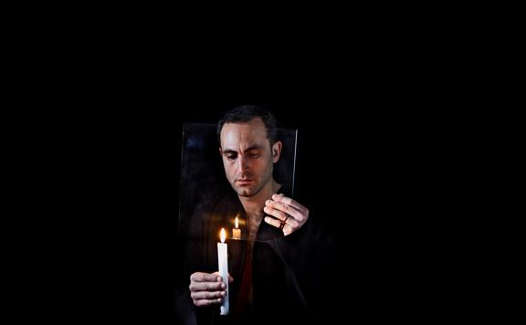 A person holding a lit candle in a dark space.