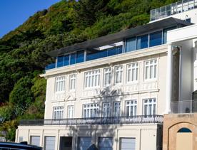 The screen location of Oriental Bay, wth pastel-coloured, Art Deco apartments, brightly-painted boat sheds, and the golden beach.