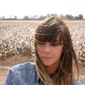 A close-up of American singer-songwriter, Charlyn Marie "Chan" Marshall, better known by her stage name Cat Power, looking down in a field.