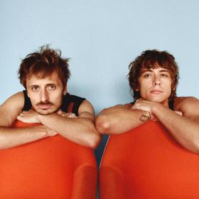 Two members of the band Lime Cordiale looking at the camera with their elbows on bean bags.