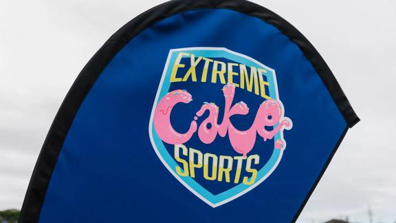 A dark blue flag with the ‘Extreme Cake Sports’ logo displayed in the centre of it.