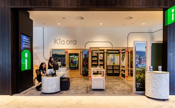 People sit at the information desk of the Wellington isite in Tākina.