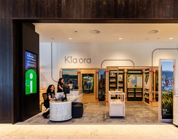 People sit at the information desk of the Wellington isite in Tākina.
