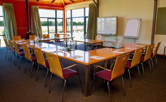 A meeting room setup at Margrain Vineyard, located in Martinborough. Tables are arranges in a U-shape with chairs, pens, papers, watch pitchers and drinking glasses.