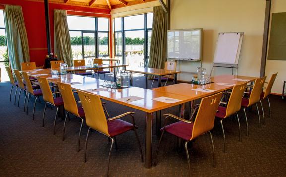 A meeting room setup at Margrain Vineyard, located in Martinborough. Tables are arranges in a U-shape with chairs, pens, papers, watch pitchers and drinking glasses. 