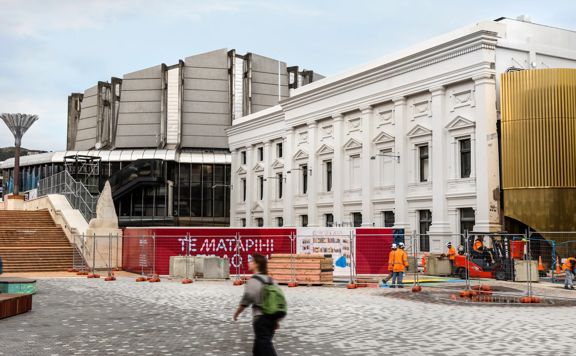 Person walking in front of Te Whare Whakarauika Wellington Town Hall with construction works happening
