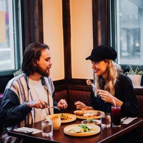 A couple enjoys food and drinks in the corner booth table at Apapacho.