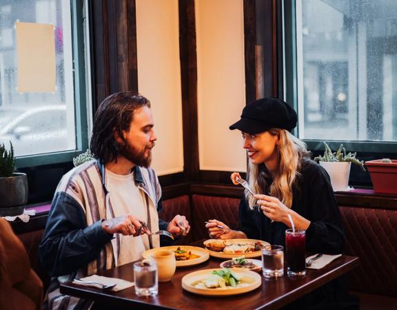 A couple enjoys food and drinks in the corner booth table at Apapacho.