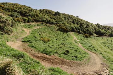 A section of the Chimney Sweep trail in Ngā Ara o Rangituhi. For mountain bikers only, the dirt track winds down a grassy hill overlooking Porirua.
