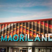 Image of Maoriland signage on top of a building. Large blue letters against textured orange and brown roof cladding.