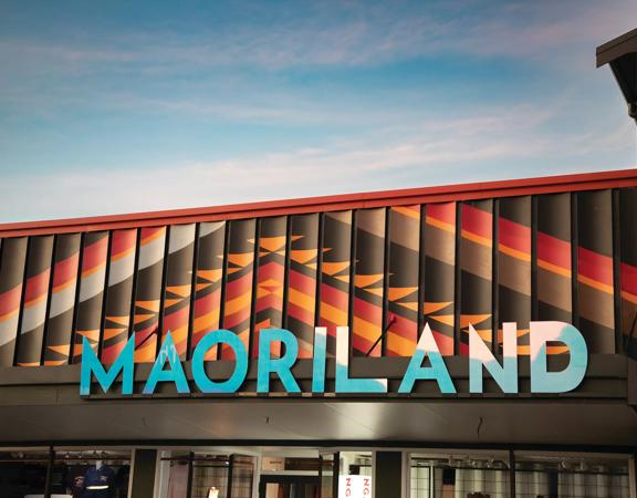 Image of Maoriland signage on top of a building. Large blue letters against textured orange and brown roof cladding.