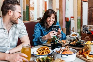 Three people eat crab and other seafood plates at The Crab Shack on Queens Wharf.