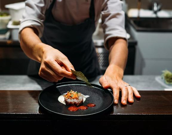 Close-up of chef finishing plating food at 50-50 restaurant at Paraparaumu Beach.