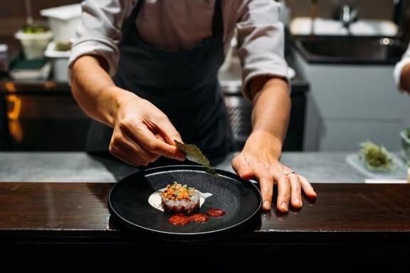 Close-up of chef finishing plating food at 50-50 restaurant at Paraparaumu Beach.