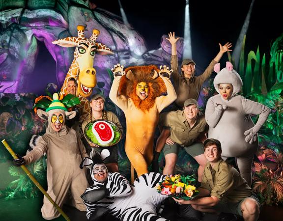 The cast of Madagascar the Musical on stage in costume posing together. 