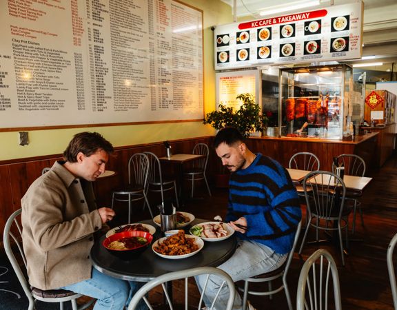 Two friends enjoying asian cuisine at K C Cafe & Takeaway.