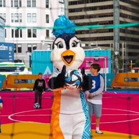 Tazuni the penguin holds a football at the Fifa unity Pitch.