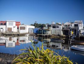 The Petone boat ramp, Hikoikoi,  with colourful boat sheds and boats in the morning sun.