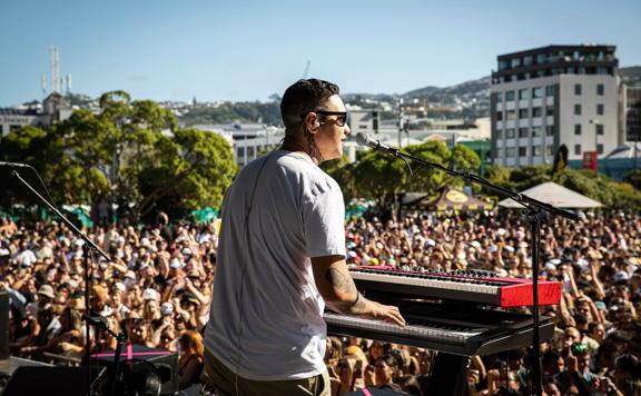 A performer at the Park stage at Jim beam Home Grown 2023 playing the keyboard and singing  to a crowd of thousands.