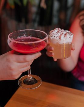Two people cheersing two cocktails at Dragonfly.