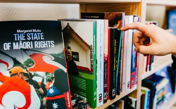 A hand reaching to pick up a book.