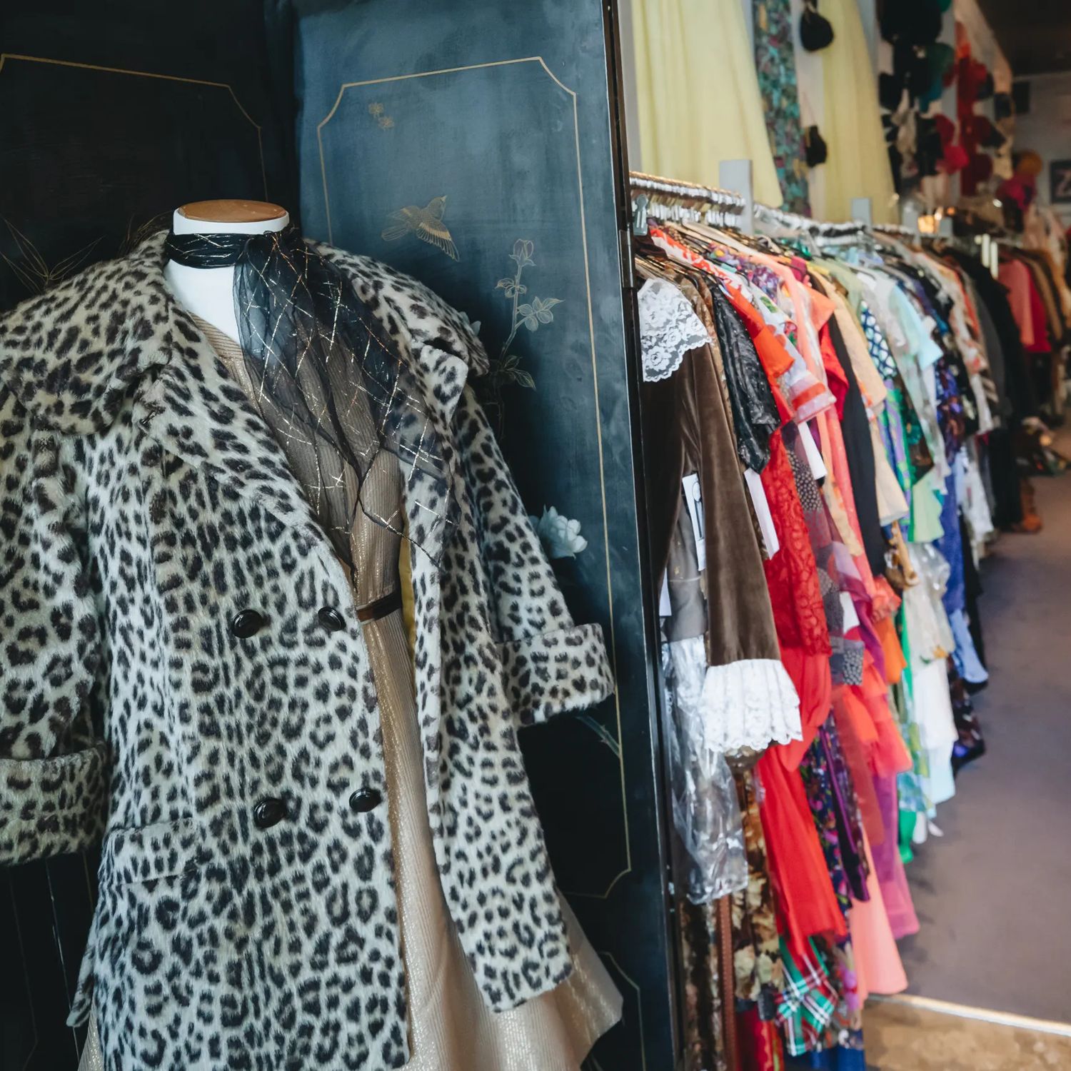 Leopard-print coat displayed beside a rack of second-hand clothing at Ziggurat.