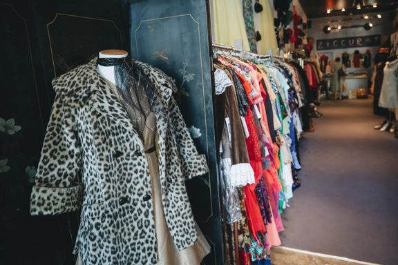 Leopard-print coat displayed beside a rack of second-hand clothing at Ziggurat.
