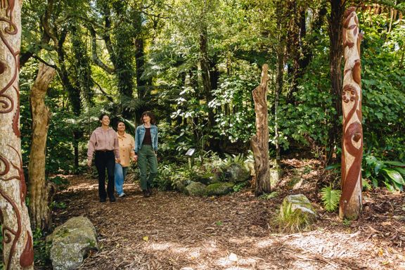 Three friends walk along a forest trail at Ōtari-Wilton's Bush.
