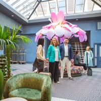 Delegates arrive at the Naumi Hotel in Wellington, a large flower sculpture is behind them.