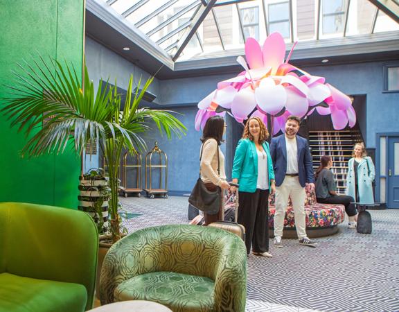 Delegates arrive at the Naumi Hotel in Wellington, a large flower sculpture is behind them.