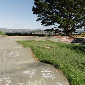 A skate park with some graffiti tags on the pavement.