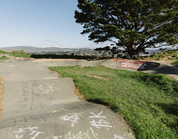 A skate park with some graffiti tags on the pavement.