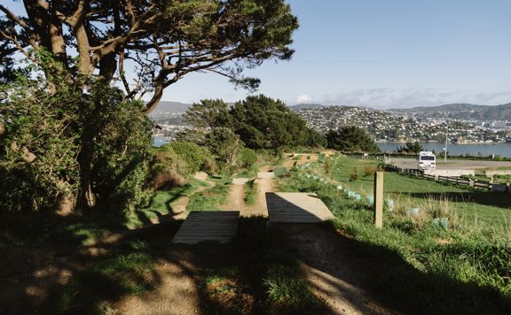Dirt mountain bike jump track platforms with Wellington city in the background.
