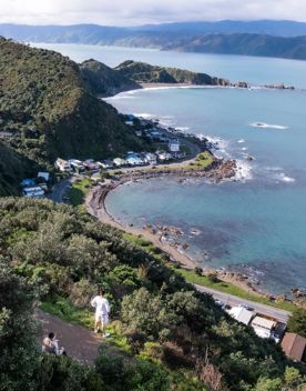 A drone shot of two hikers taking in the view of Breaker Bay from the Eastern Walkway.