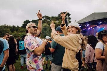 Two friends dancing in the crowd at an outdoor music festival.